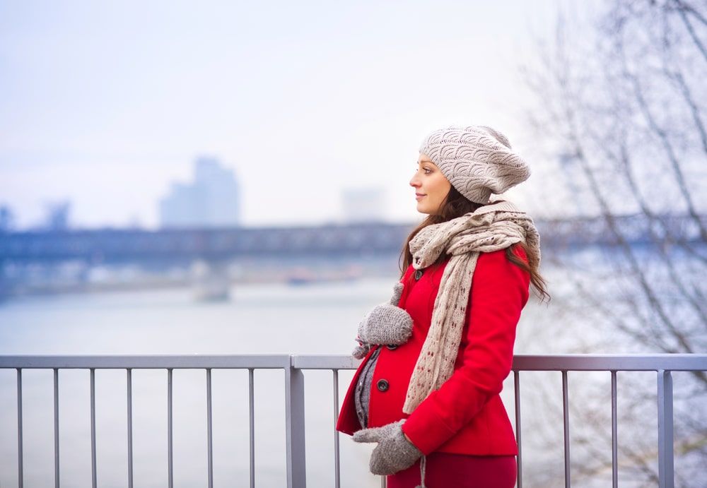 Pregnant woman looking off in the distance with her hands on her belly
