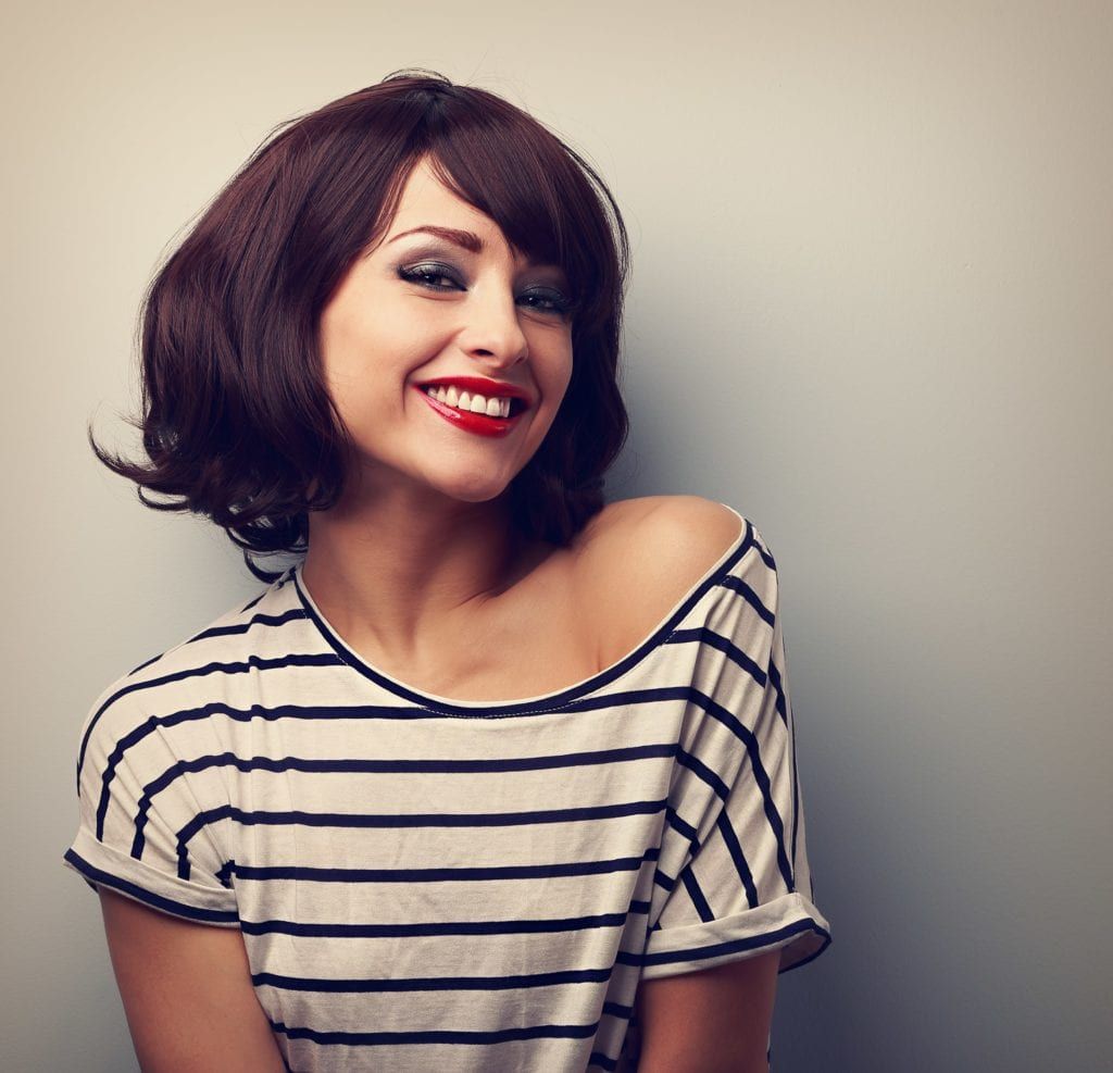 Woman in striped shirt smiling with red lipstick