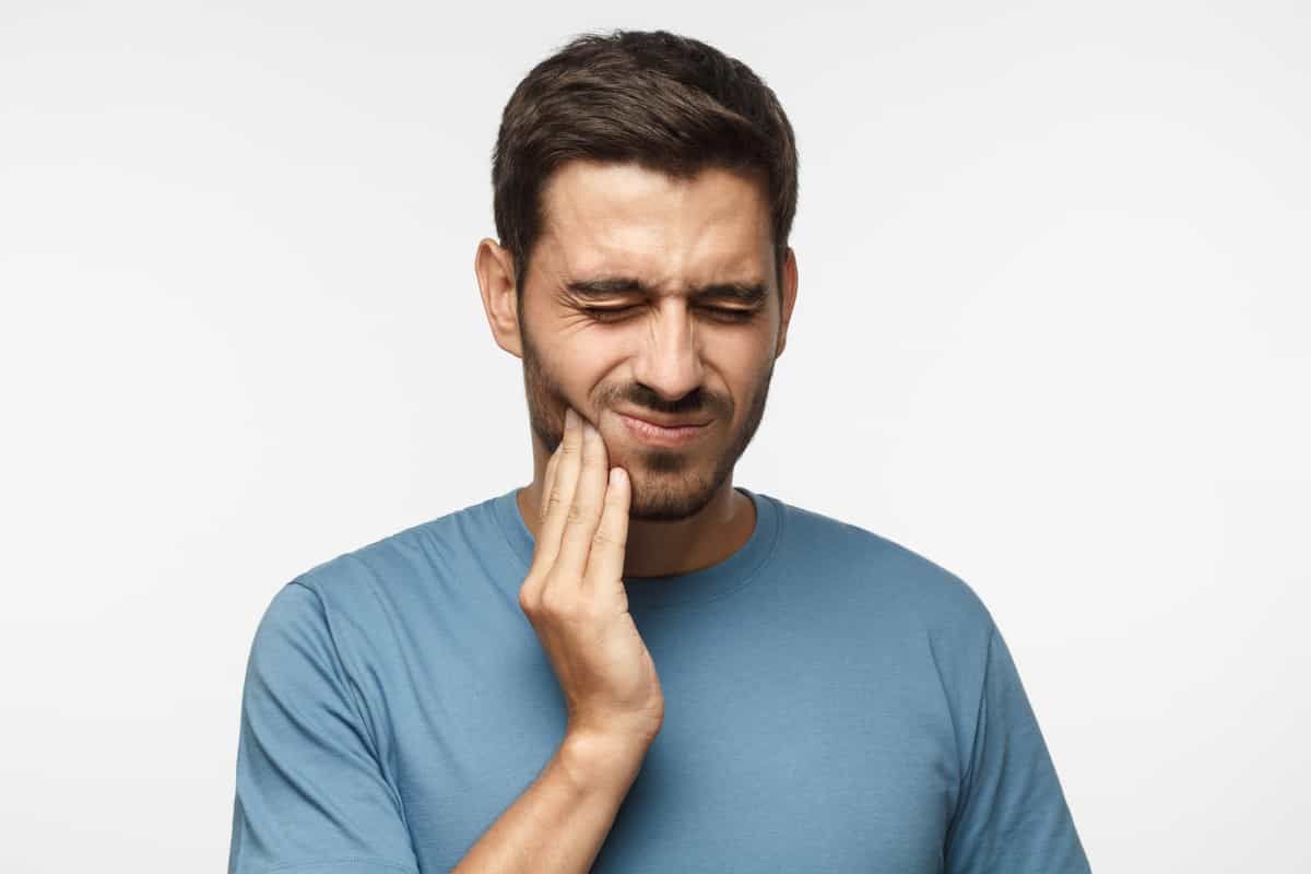 man holding his cheek in pain